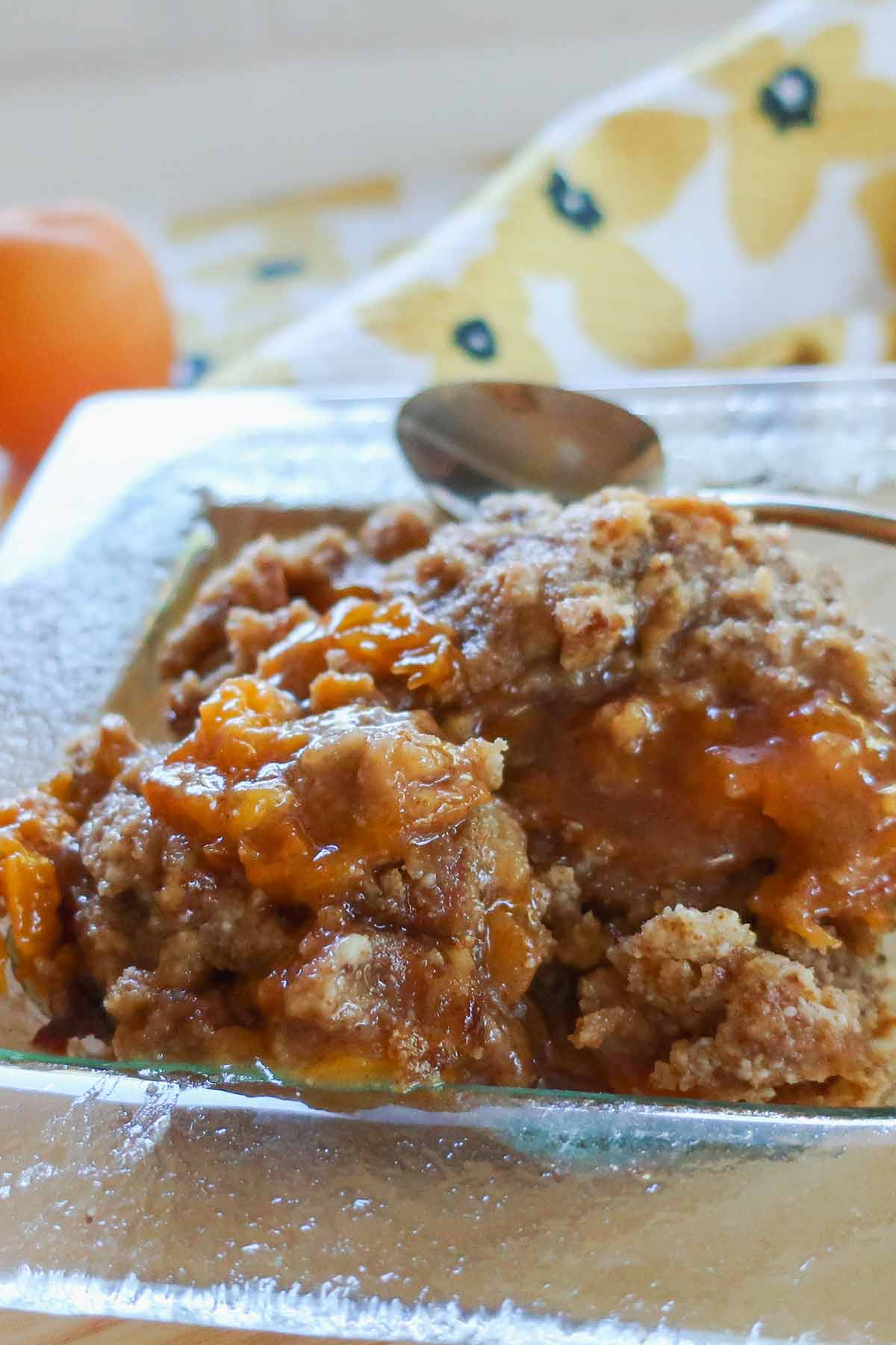 close up of a serving of apricot cobbler style dump cake in a small bowl with a spoon