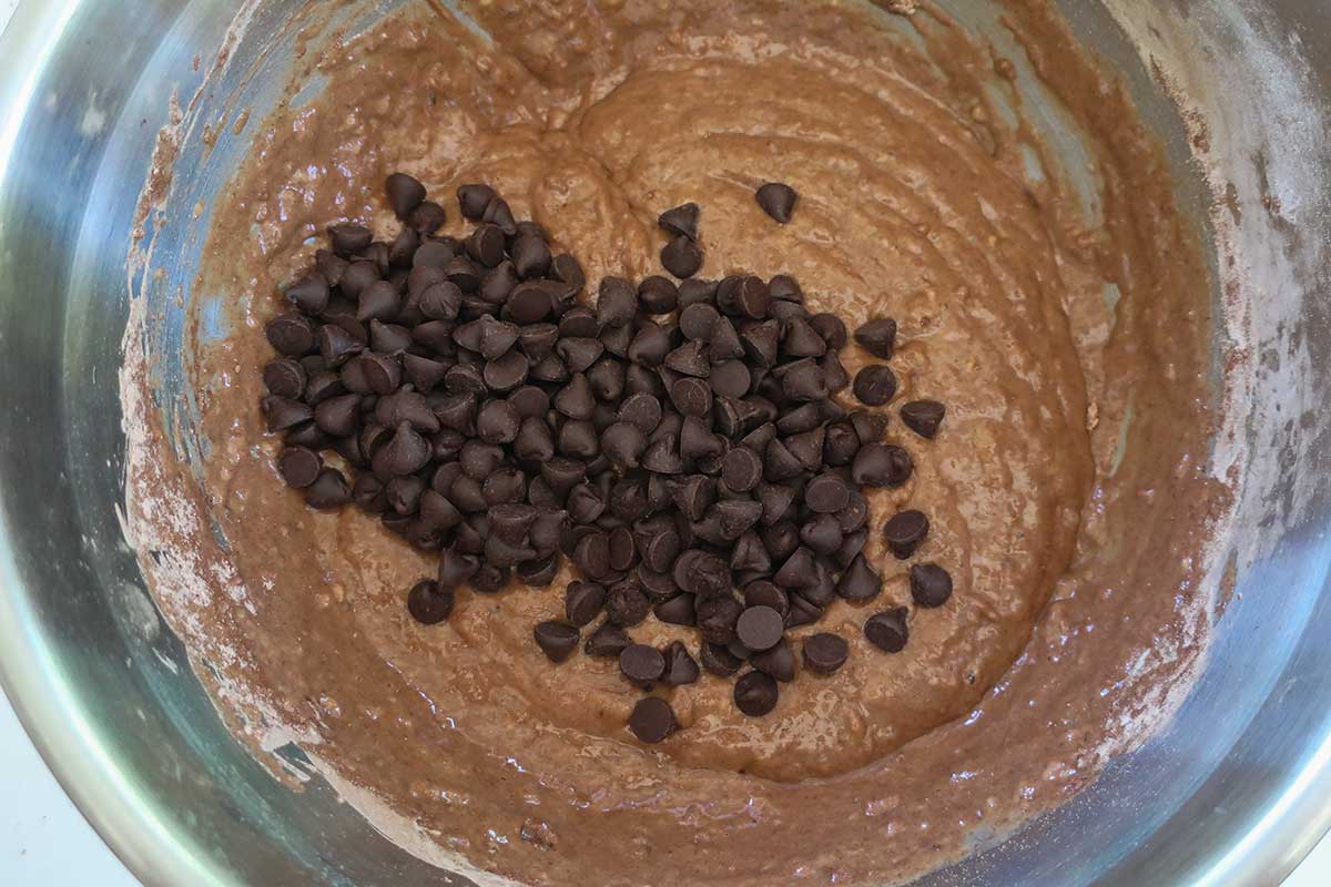 thick smooth banana muffin batter with added chocolate chips in a bowl