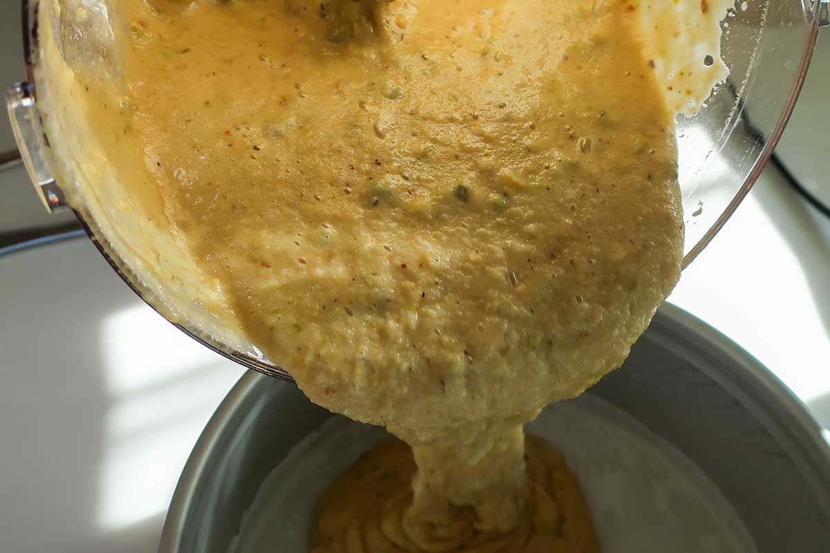 Thick batter being poured into prepared 8" cake pan