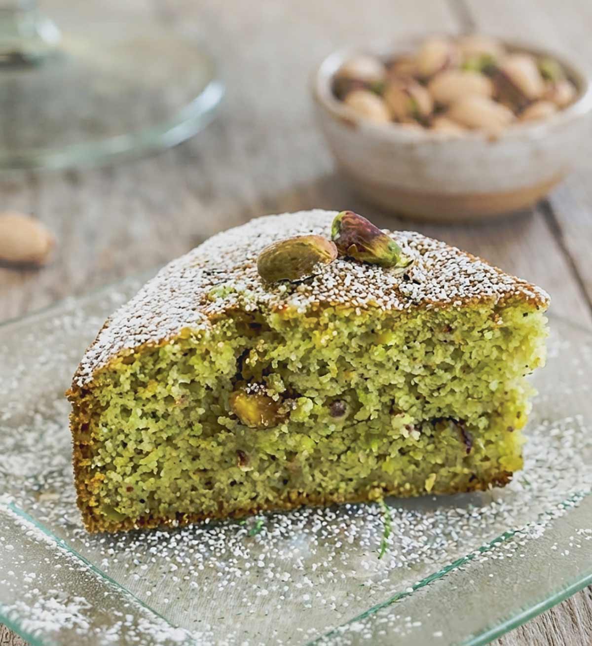 close up of a slice of green color pistachio cake with a light crumb on a dessert plate
