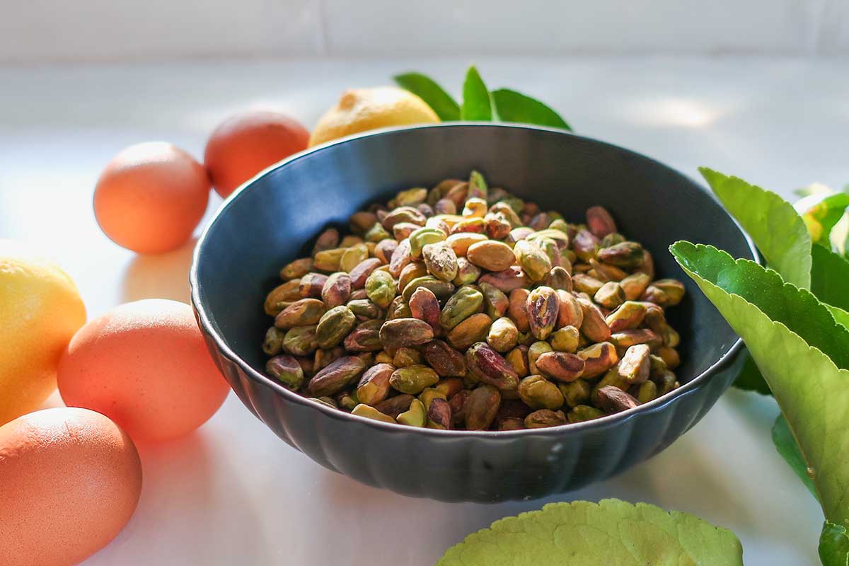 pistachios in a bowl with eggs and lemons on the side