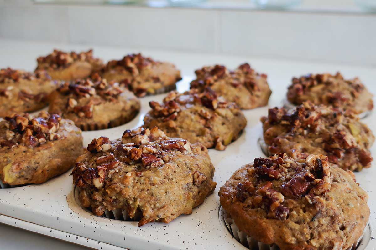 freshly baked, Bakery-Style Gluten-Free Apple Pecan Cornmeal Muffins in a muffin pan