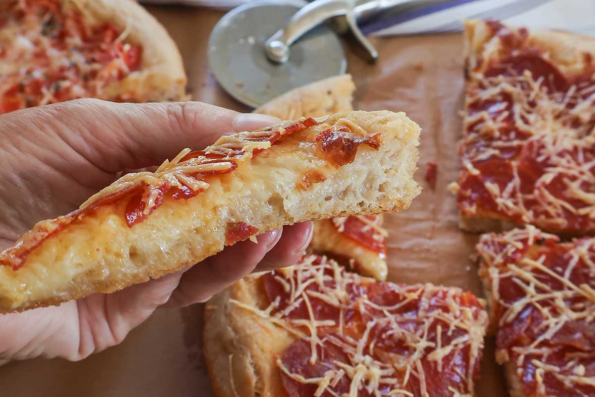close up of one slice of Chicago deep dish pizza showing light crumb puffed crust and toppings