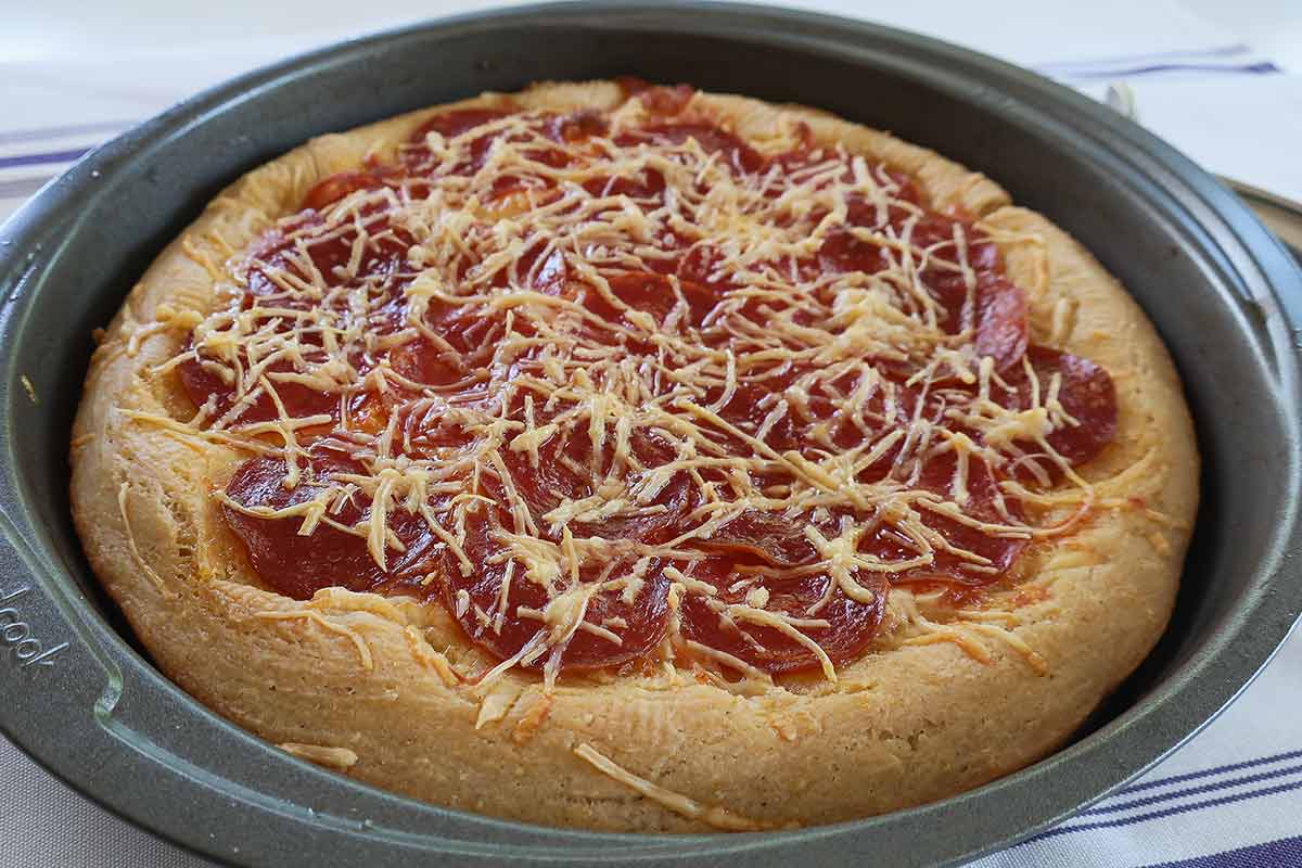 freshly baked Chicago deep dish pizza in a round 9" baking pan showing puffed golden crispy crust edges
