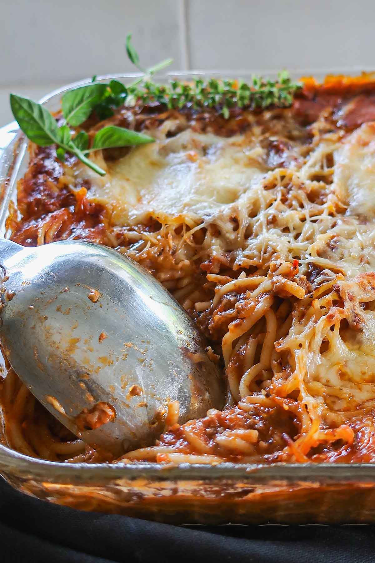 Serving of Gluten-Free Million Dollar Spaghetti Bake from the casserole dish with melted cheese and visible spaghetti strands