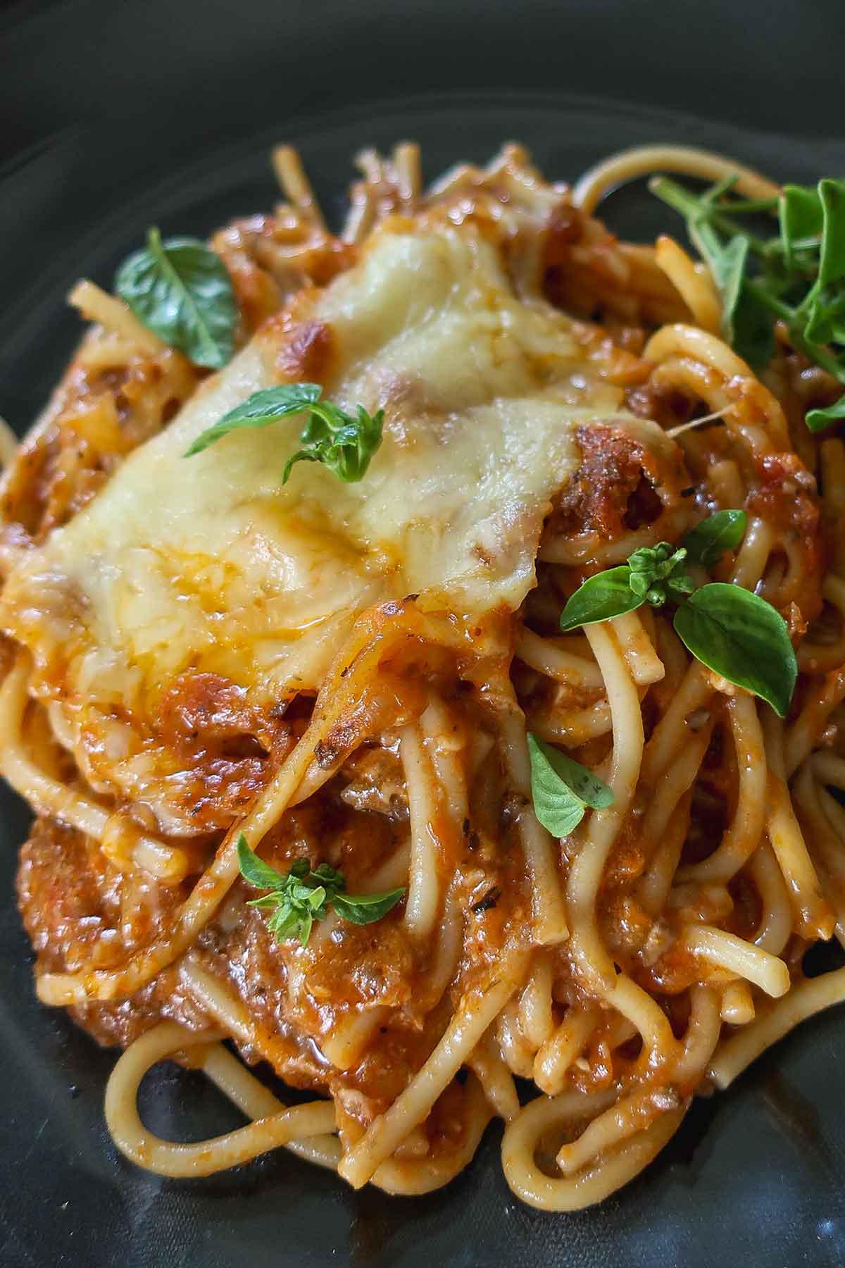 serving of Gluten-Free Million Dollar Spaghetti on a plate topped with fresh herbs