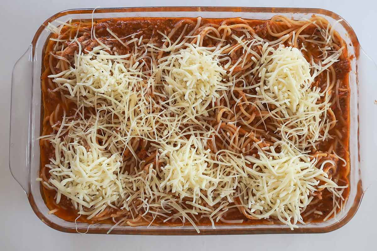 assembled Gluten-Free Million Dollar Spaghetti Bake before baking pasta coated in thick creamy sauce topped with dollop of Mozzarella and Parmesan cheese 