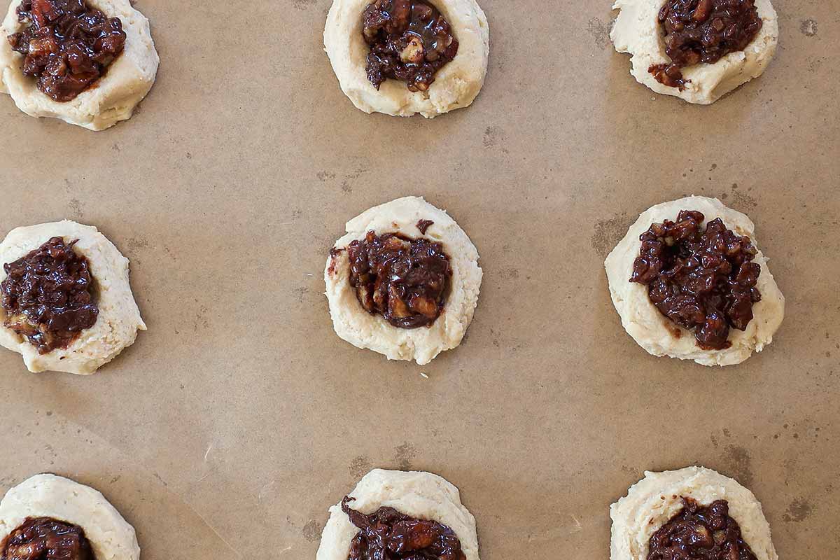 shaped cookies with pecan topping 2" apart on a lined baking sheet before baking