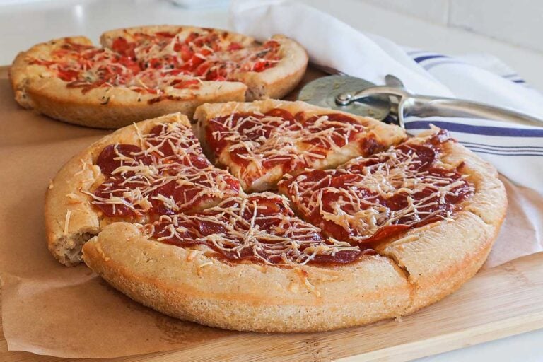 sliced gluten free deep dish Chicago pizza with cheese, pepperoni and fresh tomatoes puffed around the edges