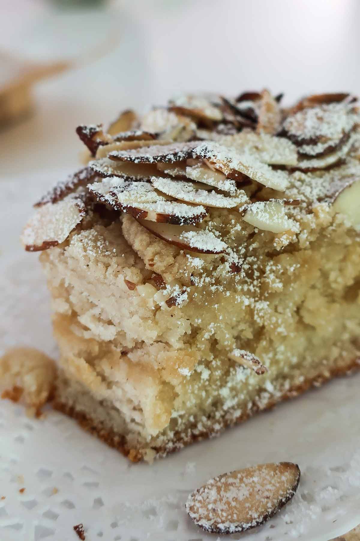close up of half a gluten free frangipane scone with buttery crumb and topped with sliced almonds and powdered sugar