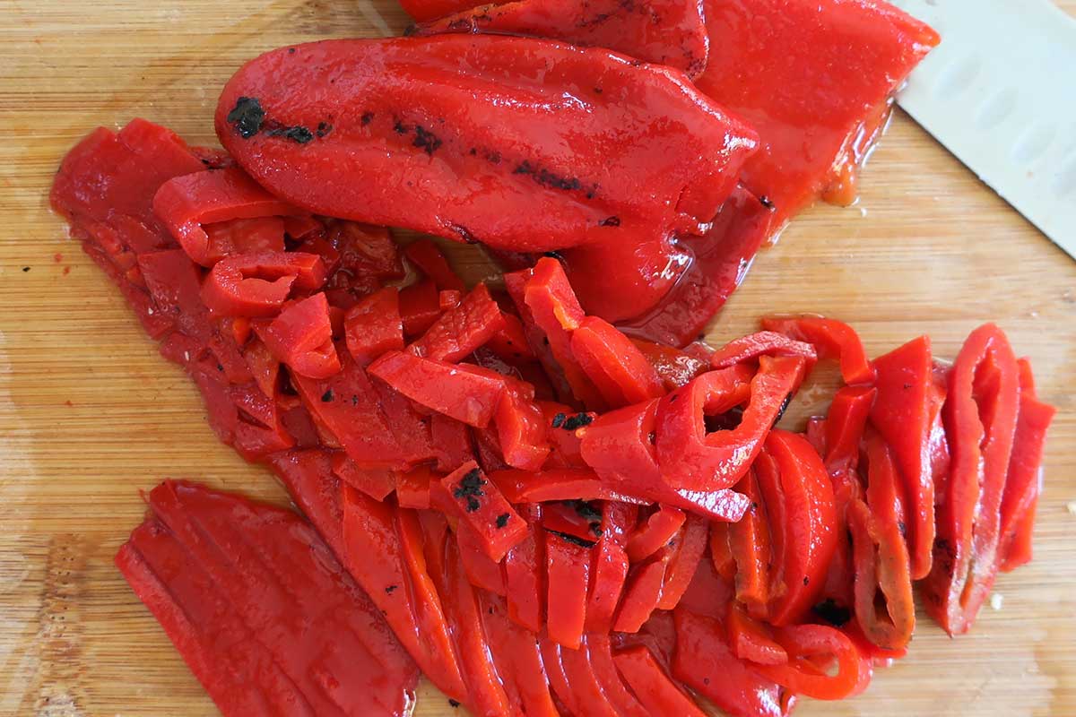 fire roasted red bell peppers sliced on a cutting board