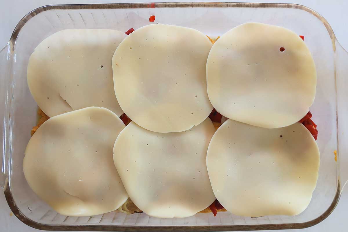 layered sweet potato lasagne topped with provolone cheese in a baking dish before baking