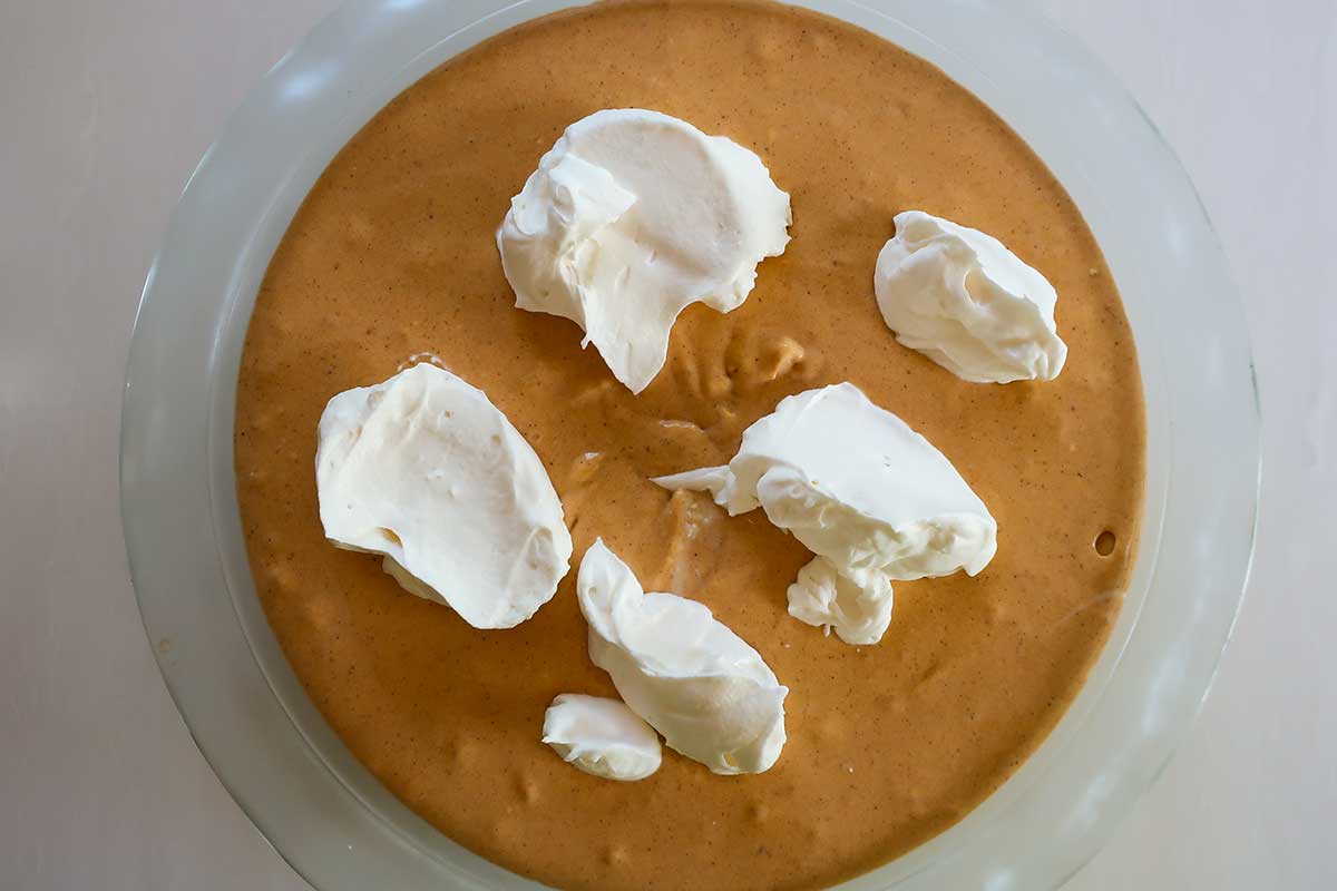 dollops of whipped cream on top of pumpkin layer before swirling into the pie